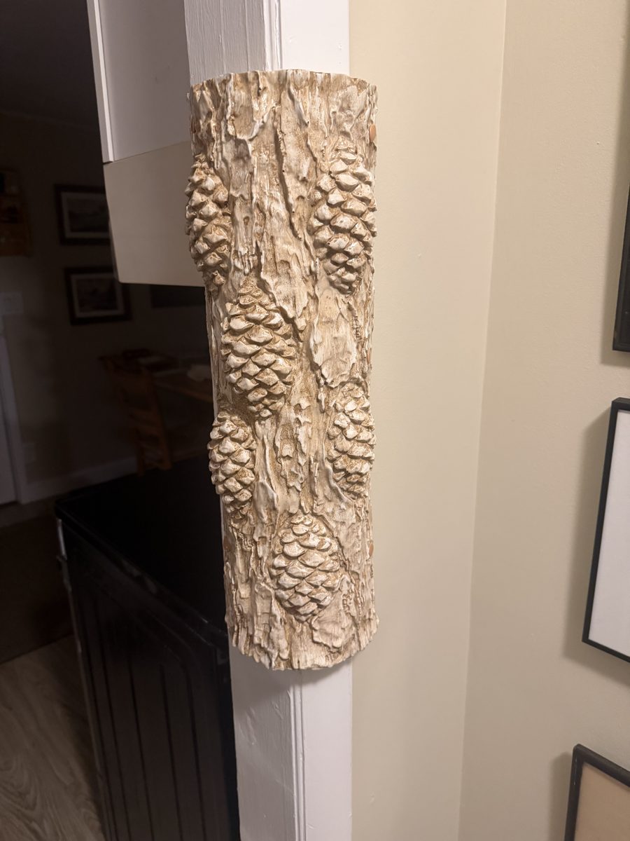 Pinecone trunk sculpture mounted on a white archway corner